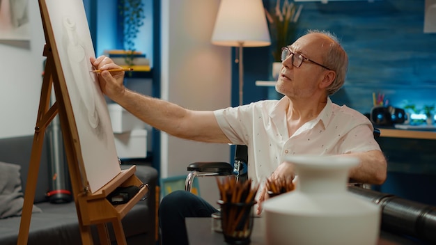 Male artist with chronic impairment drawing vase design on canvas, using artistic skills to create masterpiece. Paralyzed wheelchair user with health condition draw professional artwork.