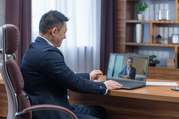 Male asian boss talking on video call with colleagues online\
rally video call boss working in classic office