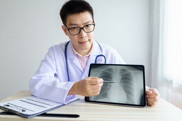 Male asian doctor working in the office hospital. discussing x-ray by using digital tablet.