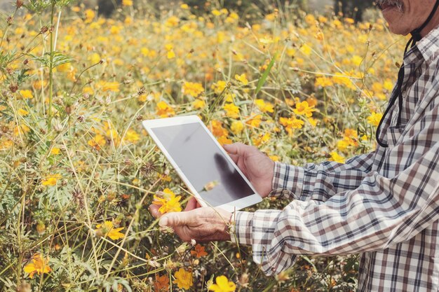 フラワーファームでデジタルタブレットを使用して男性のアジアの農家