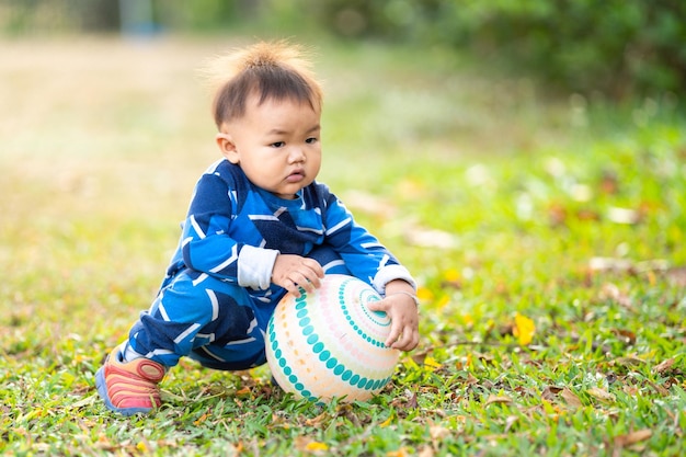 屋外の裏庭でサッカーを持って遊んでいる男性のアジアの子供