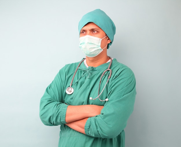 남성 아시아 외과 의사, 외과 의사 마스크를 쓰고 청진을 보여주는.