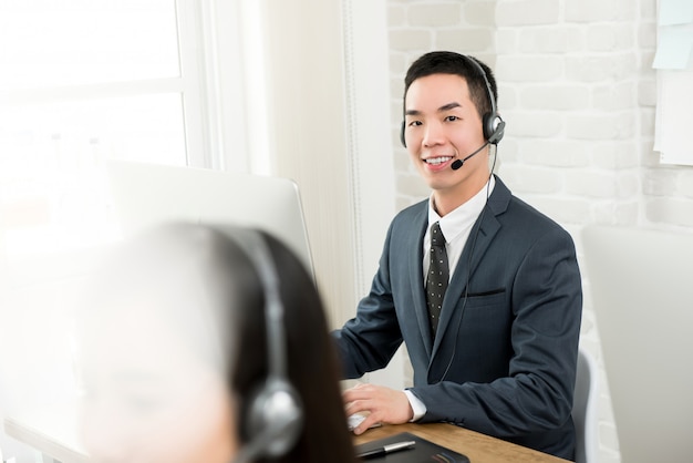 Male Asian telemarketing customer service agent working in call center