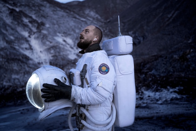 未知の惑星での宇宙ミッション中にヘルメットを脱ぐ男性宇宙飛行士