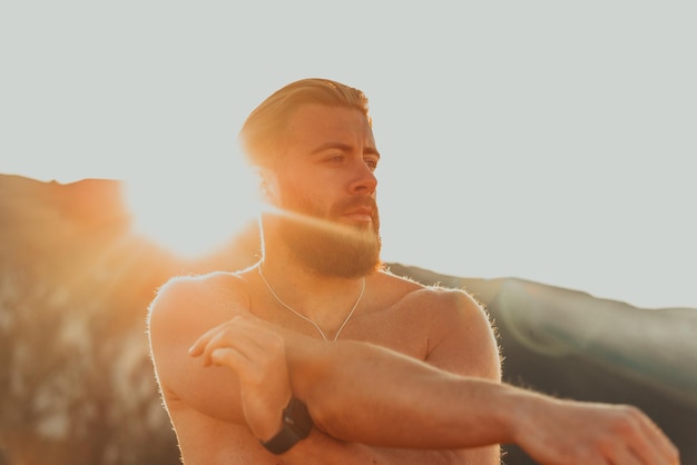 Male athlete doing arm stretching exercise on top of a mountain.