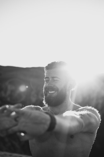 Male athlete doing arm stretching exercise on top of a mountain.