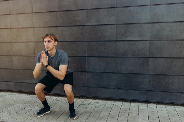 Male athlete doing exercises on a black wall