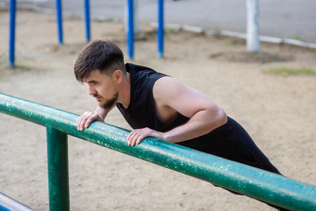 Male athlete doing pushups on the sports ground closeup