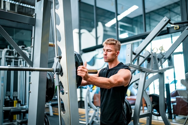 Atleta maschio che si esercita in palestra sollevando pesi tirando le articolazioni