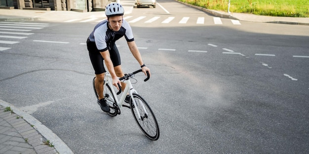 A male athlete in gear rides a bike for a highway workout