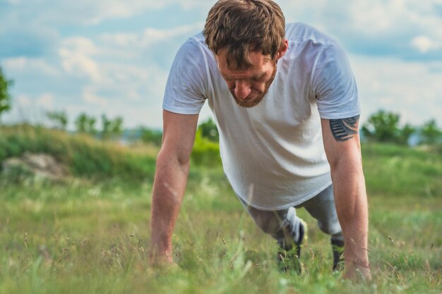 Male Athlete Performing PushUps on Grass in Sunny Outdoor Park Man athlete is engaged in a robust training session performing pushups on a grassy field in a sunny outdoor park