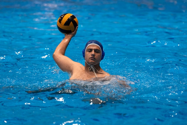 Foto atleta maschio che gioca pallanuoto in piscina coperta