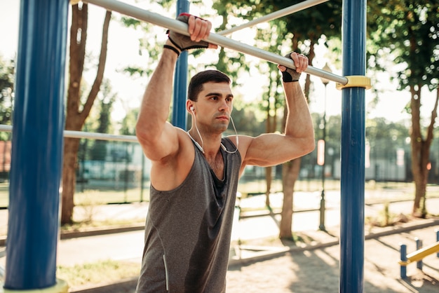 Male athlete poses on horizontal bar outdoor