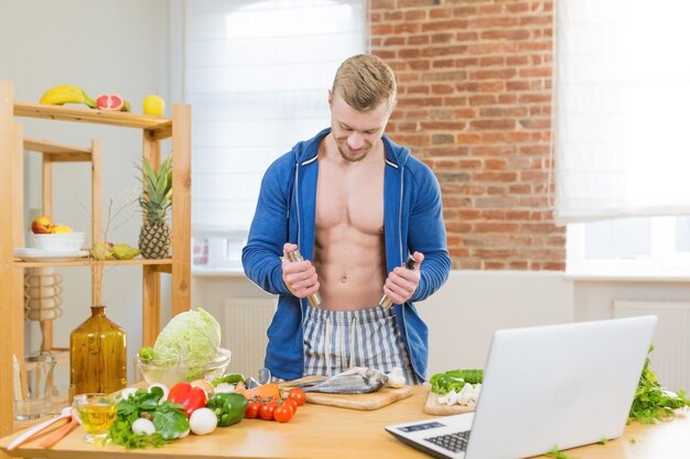 Male athlete preparing healthy food at home in the kitchen, studying online