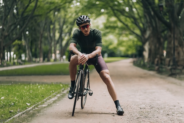 Male athlete resting on bike after training at park