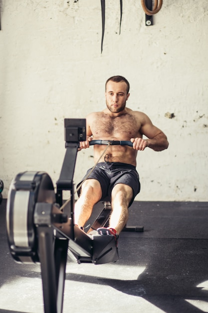 Male athlete on rowing machine on cross competition