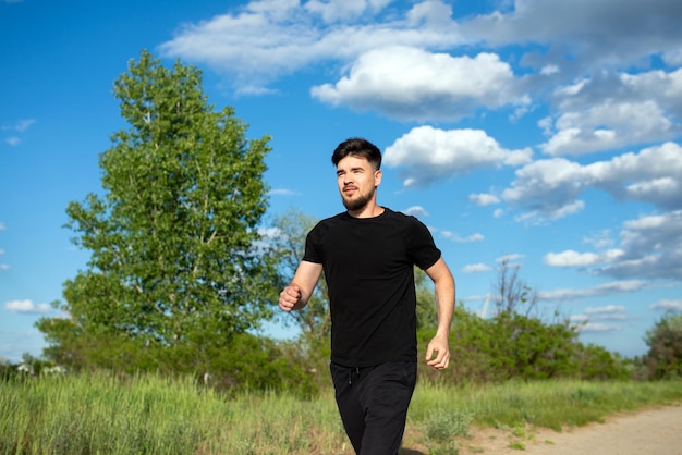 Мужчина-спортсмен бежит на природе против неба крупным планом