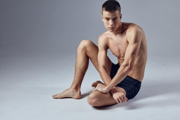 Male athlete sitting on floor with pumped up body posing High quality photo