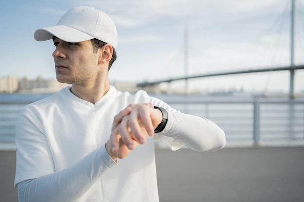 A male athlete uses a smartwatch on his hand to count calories\
and pulse while training to run