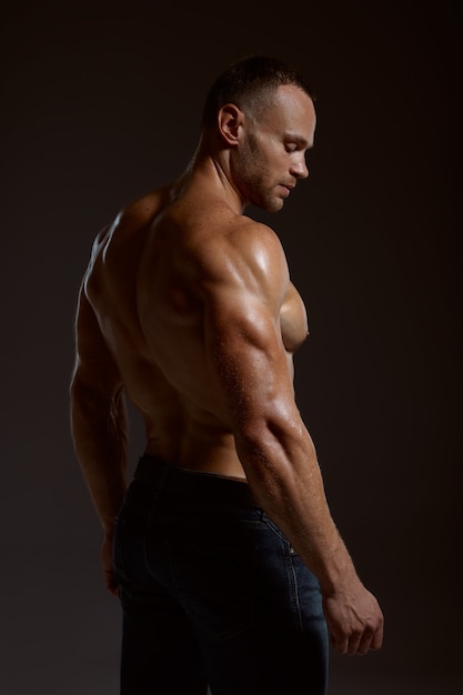 Male athlete with muscular body poses in studio