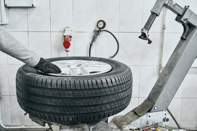 Мужской автоматический техник заменяя старую шину на колесе в гараже