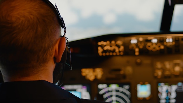 Aviatore maschio che utilizza la maniglia e il parabrezza nella cabina di pilotaggio per pilotare l'aereo, strozzando il motore di potenza al decollo. comandare l'equipaggio e utilizzare il cruscotto del pannello di controllo. avvicinamento.