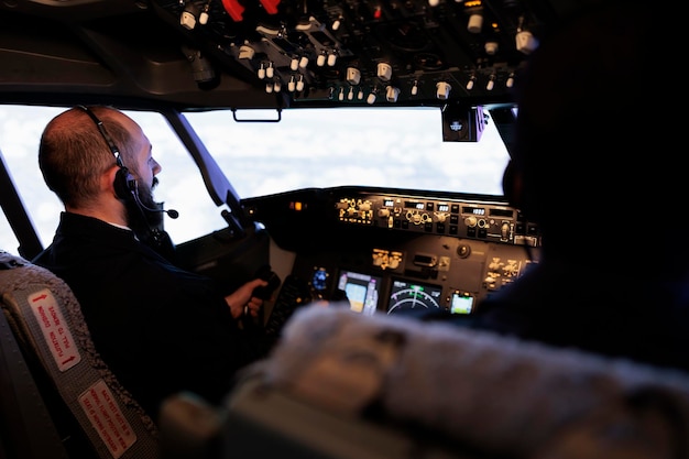 Male aviators flying airplane from cockpit with control panel\
and dashboard command, pushing power buttons to travel. aircrew\
members using radar switch and navigation compass to fly.