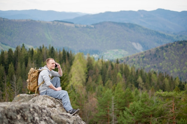 Male backpacker sitting on the peak of rock