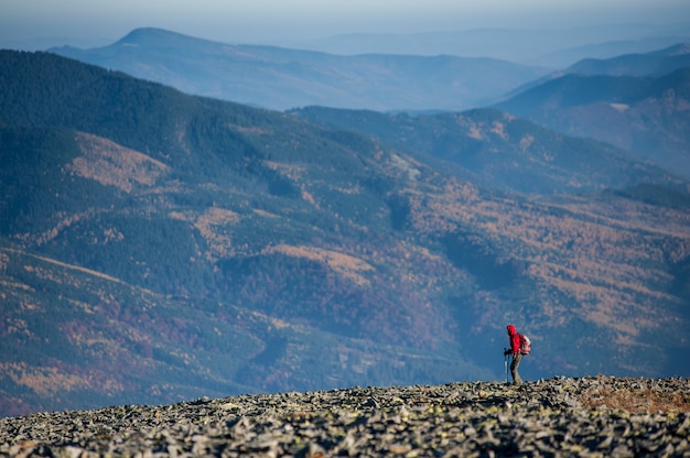 Male backpaker walking on the rocky top of the mountain