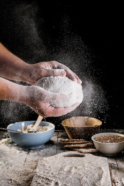 Male baker's hand dusting dough with flour