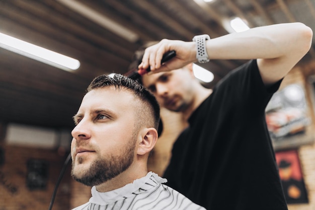 Male barber drying hair of hipster