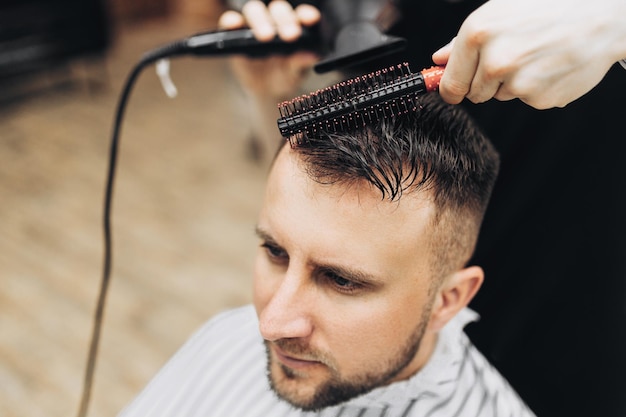 Male barber drying hair of hipster