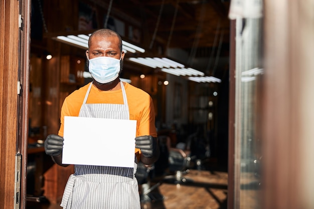 Male barber in medical mask holding blank card template