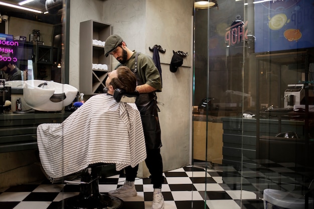 Photo male barber trimming his client's beard