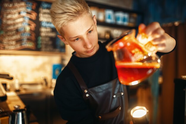 男性のバリスタがコーヒーポットの沈殿物をチェックします