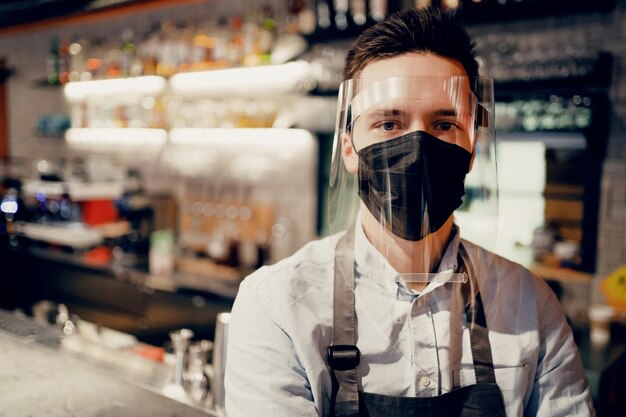 Un dipendente barista maschio prepara e vende caffè da portare via tazza di carta con un drink