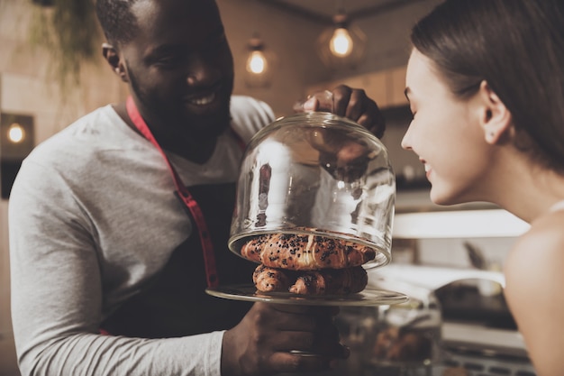 Male barista helps a girl to choose a dessert