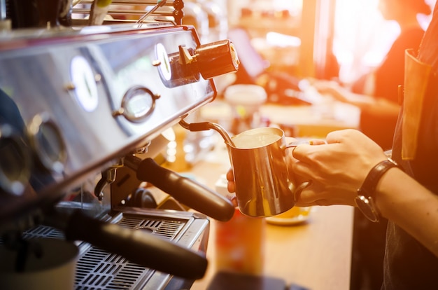 男性のバリスタは、コーヒーショップカフェでコーヒーカフェラテアートを作る