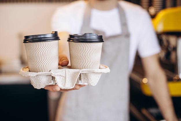 板紙のカップでコーヒーを提供する男性のバリスタ