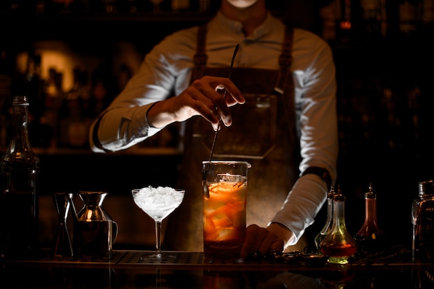 Male bartender stirring a cocktail in the measuring glass cup