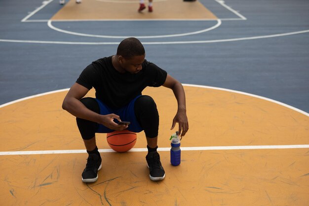 Male basketball player using mobile phone