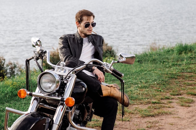 Male biker sitting on the motor bike and smoking cigarette