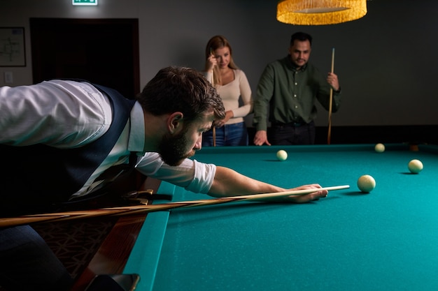 Male billiard player finding best solution and right angle at billard or snooker pool sport game, he is concentrated