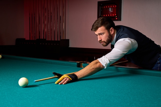 Male billiard player finding best solution and right angle at billard or snooker pool sport game, professional billiard player is concentrated