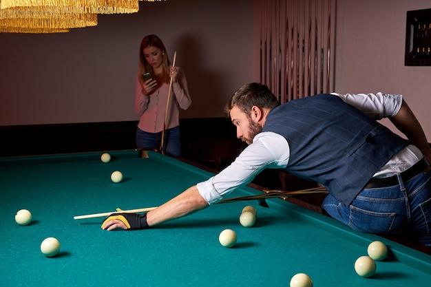 Male billiard player finding best solution and right angle at billard or snooker pool sport game, professional billiard player is concentrated