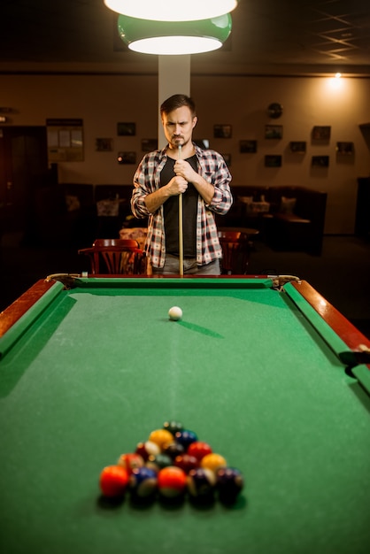 Male billiard player with cue at the table