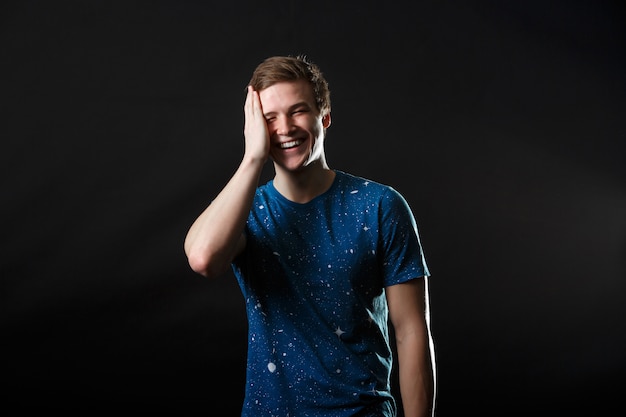 A male in blue t-shirt standing and laughing