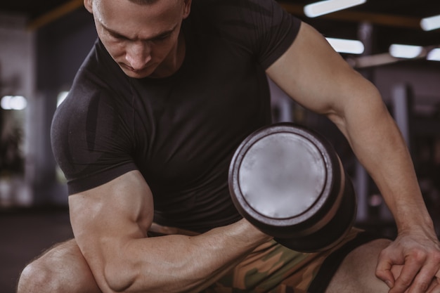 Male bodybuilder lifting dumbbells at the gym