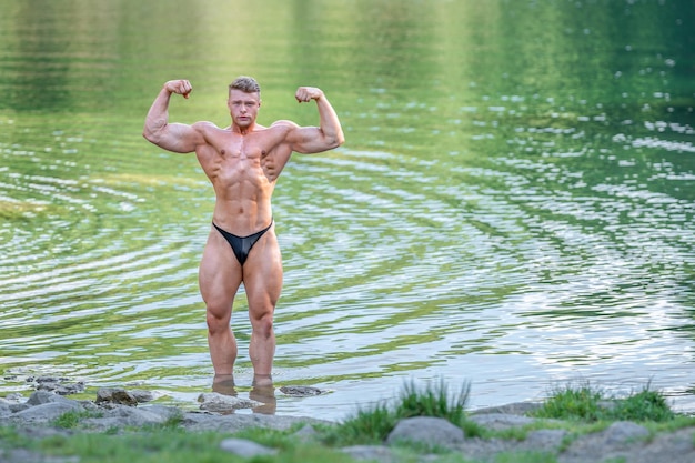 Мужской бодибилдер в воде на природе