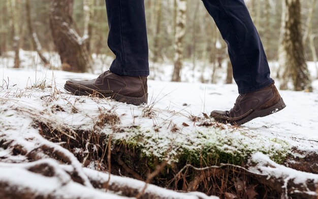 雪道、側面図の男性のブーツ。冬の森を歩いたり散歩したりする足。